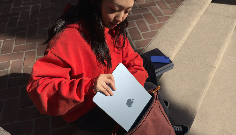 一位学生将 MacBook?Air 放入背包中